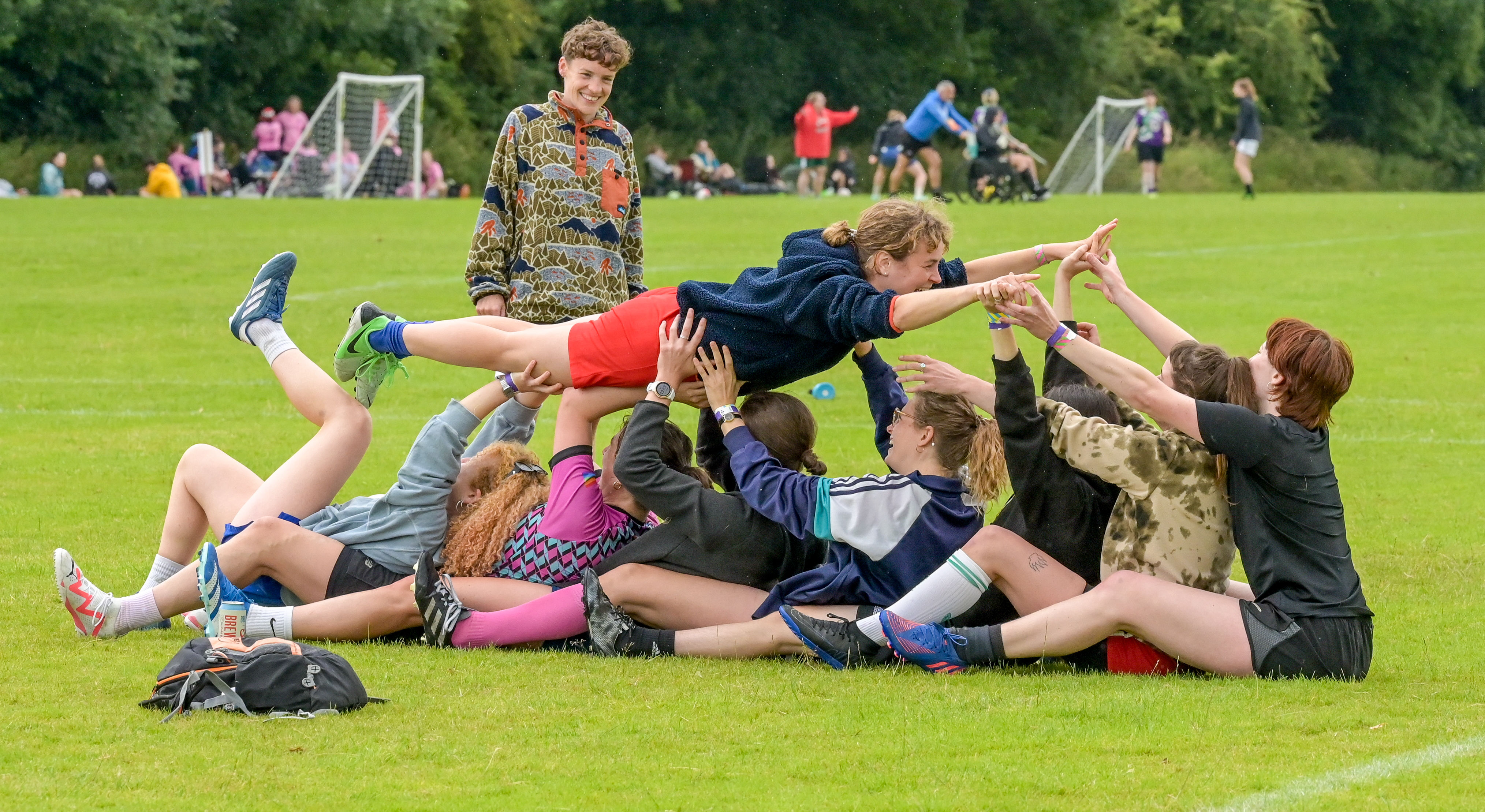 A group of players sat in a row holding another player in the air